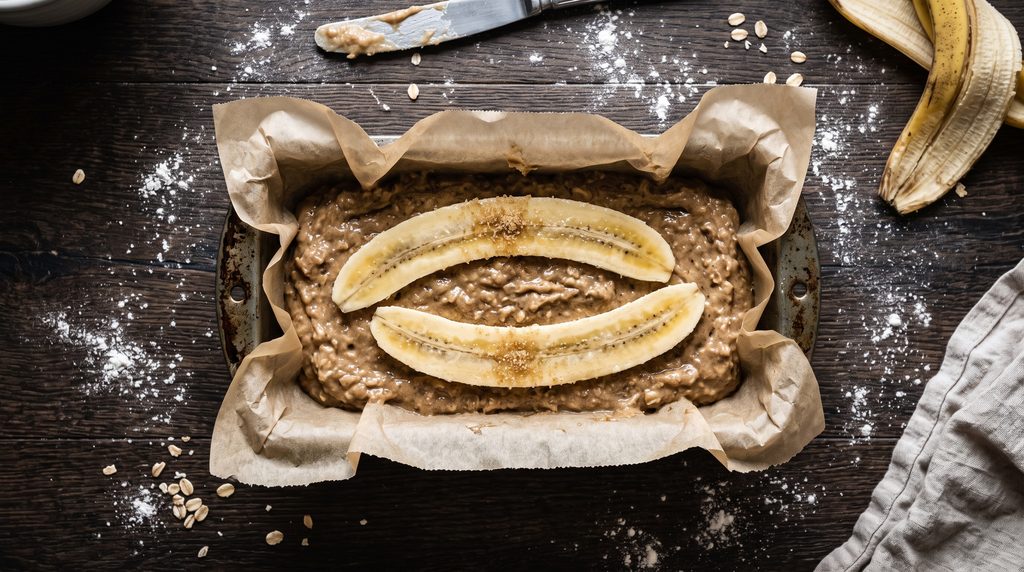 Best Banana Bread Recipe: Easy 5-Step Brown Butter Loaf 4 Banana bread batter in a parchment-lined loaf pan with sliced bananas on top before baking.